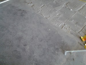 In process concrete floor preparation of previously installed tiles with remaining grout